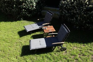 Two lounge chairs with a small table between them, set on a grassy lawn. - Holiday home in Wingst with swimming pool (Wingst)