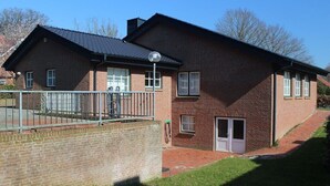 A two-story brick building with a flat roof, a single visible door, and a small attached garage. - Holiday home in Wingst with swimming pool (Wingst)