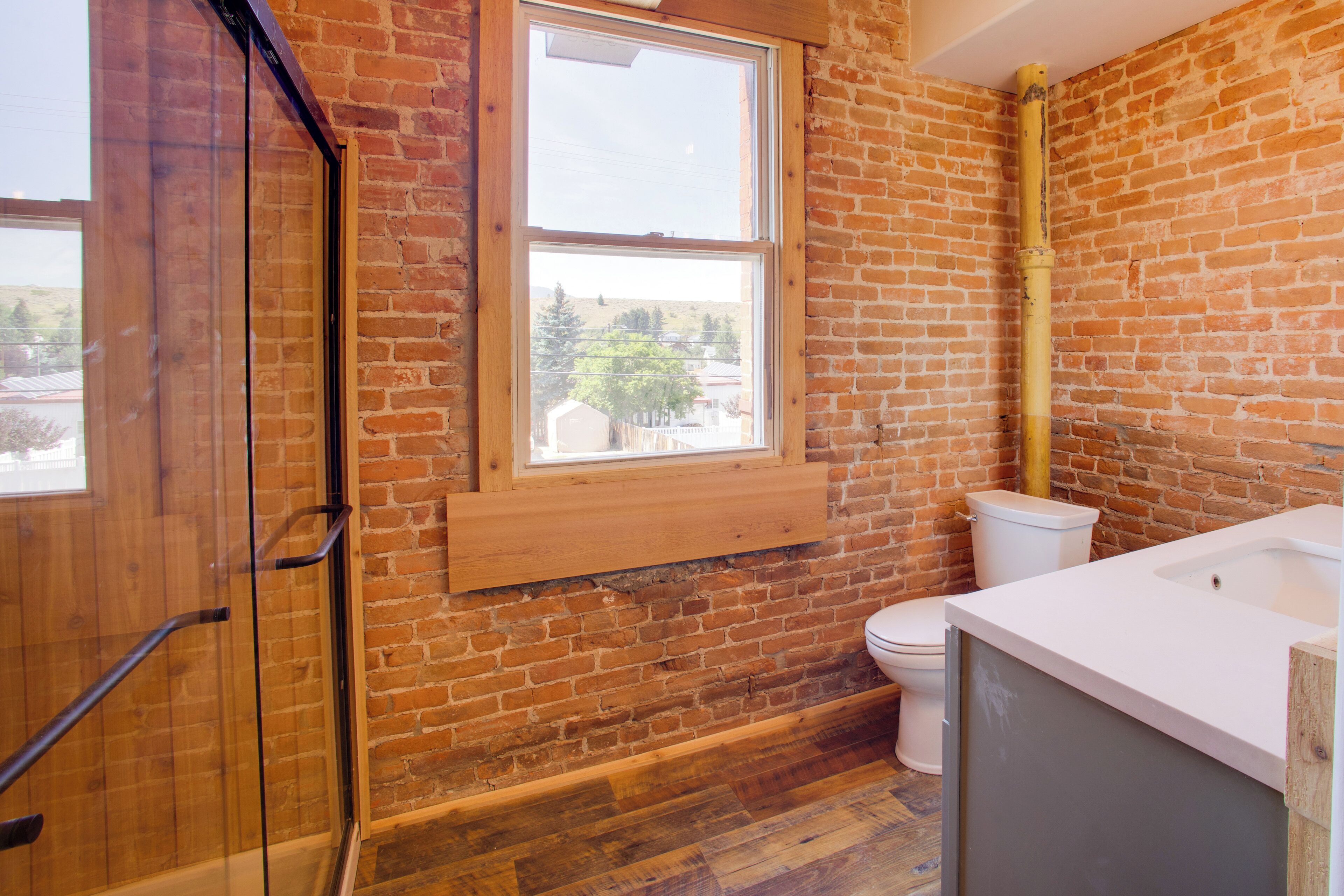Ein Badezimmer mit Holzboden, Toilette und Fenster.