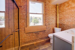 Ein Badezimmer mit Holzboden, Toilette und Fenster.