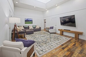 Una sala de estar amplia con un tapete grande, un sofá, una silla y una mesa de centro.