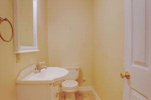 Ein Badezimmer mit Waschbecken, Toilette und einer Tür mit einem runden Knauf.