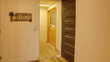 A hallway with a wooden door, a welcome sign, and a bulletin board.