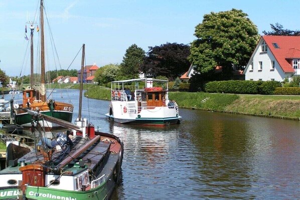 Un canal con barcos, una casa de techo rojo y vegetación.
