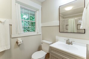 Ein Badezimmer mit Toilette, Waschbecken und einem fenster mit Vorhängen.
