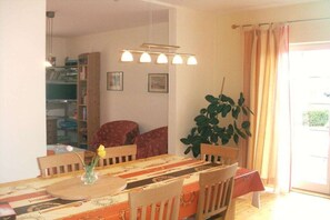 A dining area with a table, chairs, a plant, and a bookshelf. - Holiday home with 2 bedrooms (Bockhorn\/Bredehorn)