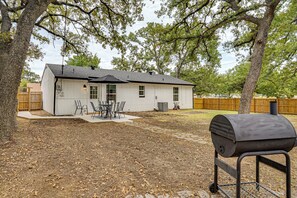 A single-story house with a patio, a grill, and a fenced yard. - Explore Arlington! Centrally Located Extended Stay (Arlington)