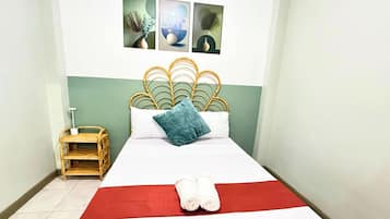 A hotel room with a bed, a small wooden side table, and a wall-mounted picture.