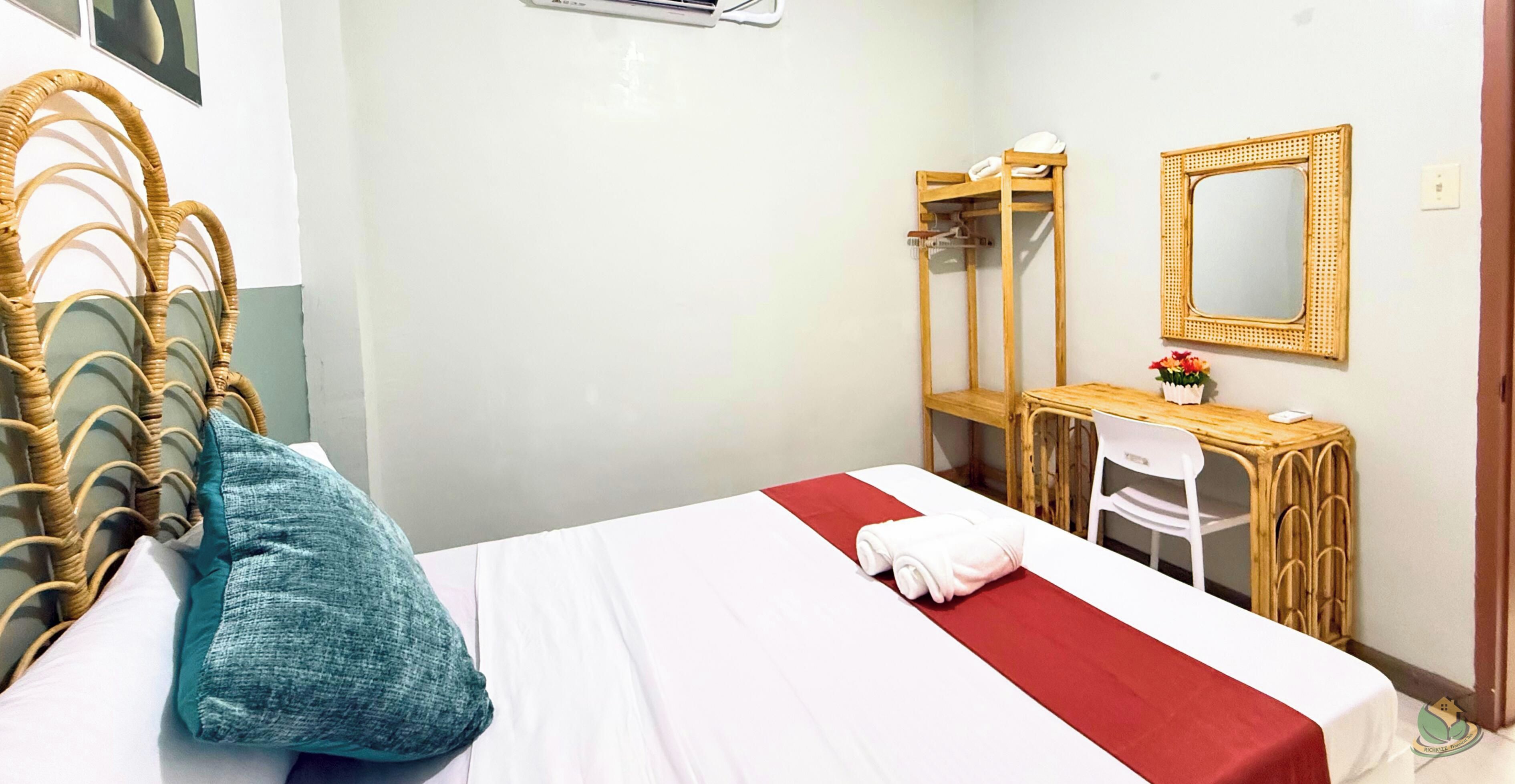 Una habitación de hotel con una cama, un escritorio, una silla, un espejo y un armario.