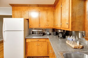 Eine Küche mit Holzschränken, einem weißen Kühlschrank, einer Mikrowelle, einer Kaffeemaschine und einem Toaster.