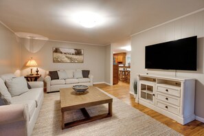 A living room with a sofa, coffee table, TV, and a painting on the wall. - Basecamp in Skyline, 10 Mi to Walls of Jericho (Scottsboro)