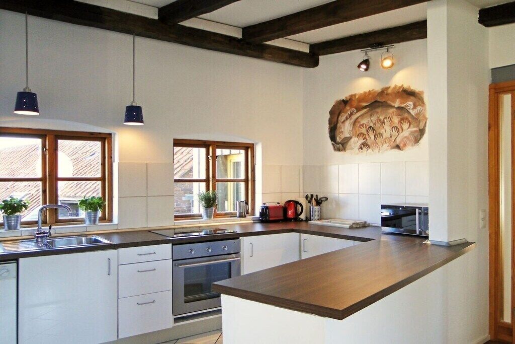 Una cocina moderna con una isla central, horno empotrado e iluminación colgante.