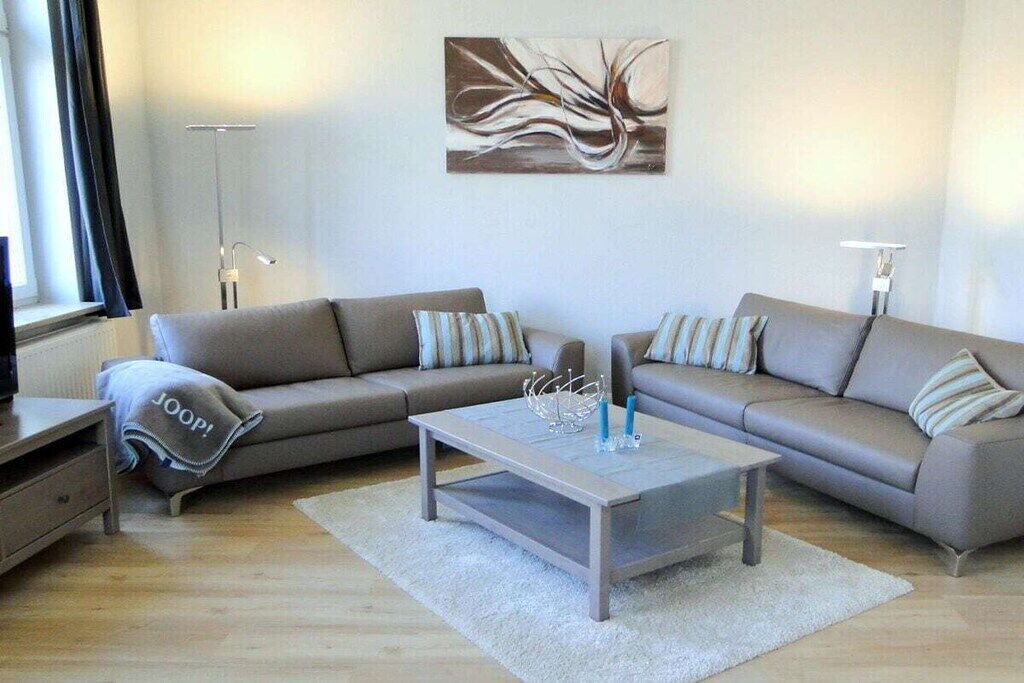 Ein modernes Wohnzimmer mit zwei Sofas, einem Couchtisch und einer Stehlampe.