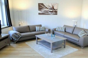 Un salon moderne avec deux canapés, une table basse et un lampadaire.