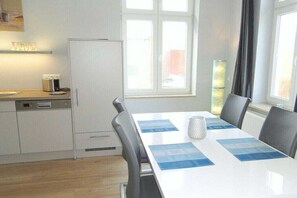 Une cuisine avec un réfrigérateur blanc, une machine à café et une table à manger avec des chaises.