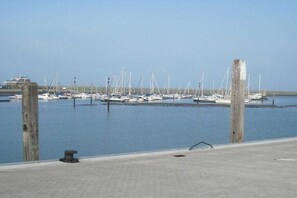 Ein Yachthafen mit mehreren angedockten Booten, einem klaren Himmel und einer Betonpromenade im Vordergrund.