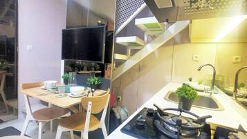 A compact kitchen with a gas stove, a sink, and a dining area with chairs and a table.
