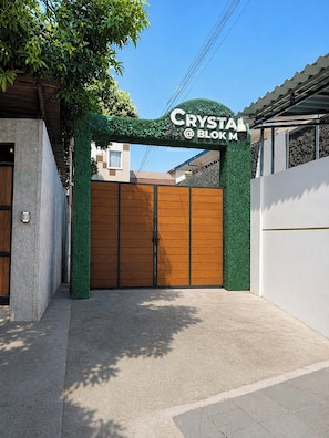 A gated entrance with a sign reading 'CRYSTAL @ BOKM' and a green wall with foliage. - Crystal at Blok M (Jakarta)