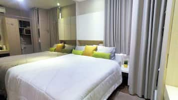 A hotel room with a large bed, a bedside table with a lamp, a potted plant, and a mirror.