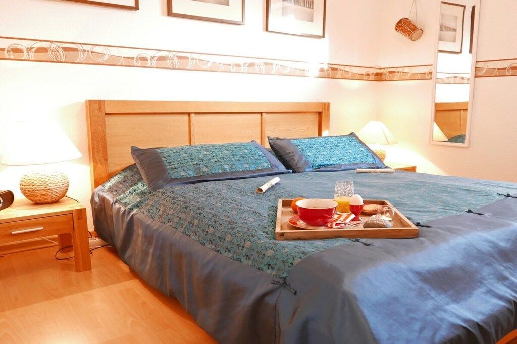 Ein Hotelzimmer mit einem Bett, einem Nachttisch, einer Lampe und einem Tablett mit Frühstücksgegenständen.
