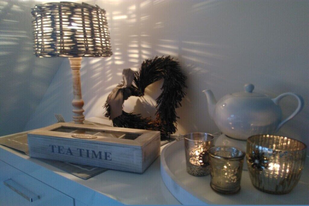 Une table avec une théière, une tasse à thé, une boîte étiquetée « HEURE DU THÉ », un chandelier et un objet décoratif.