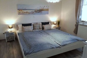 A bed with a striped bedspread, bedside lamps, and decorative pillows. - Holiday apartment with 2 bedrooms (Norden)