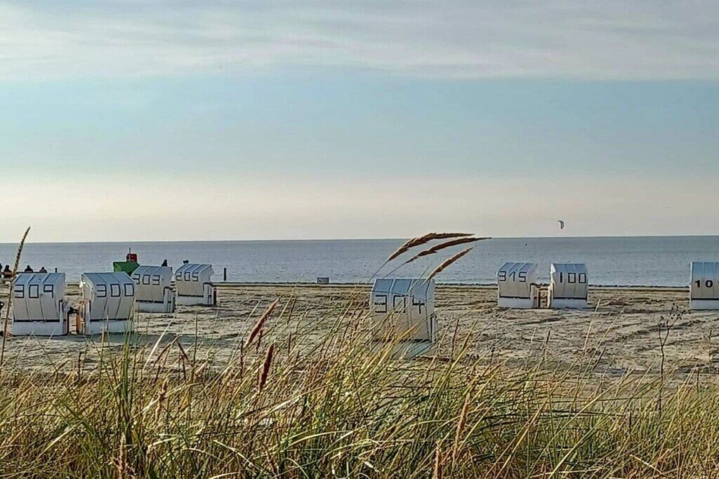 Ein Strand mit Reihenhäusern und einem Leuchtturm in der Ferne.