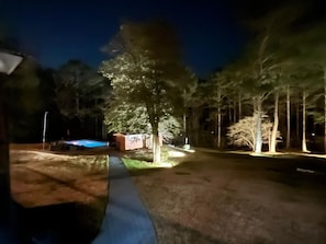 A nighttime outdoor area with a pathway, trees, and a pool. - 6BR Fayetteville Retreat | Pool, Hot Tub & Pets (Fayetteville)