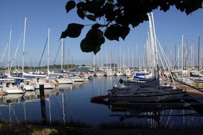 Un port de plaisance où de nombreux bateaux sont amarrés, l’eau est calme et le ciel est dégagé.