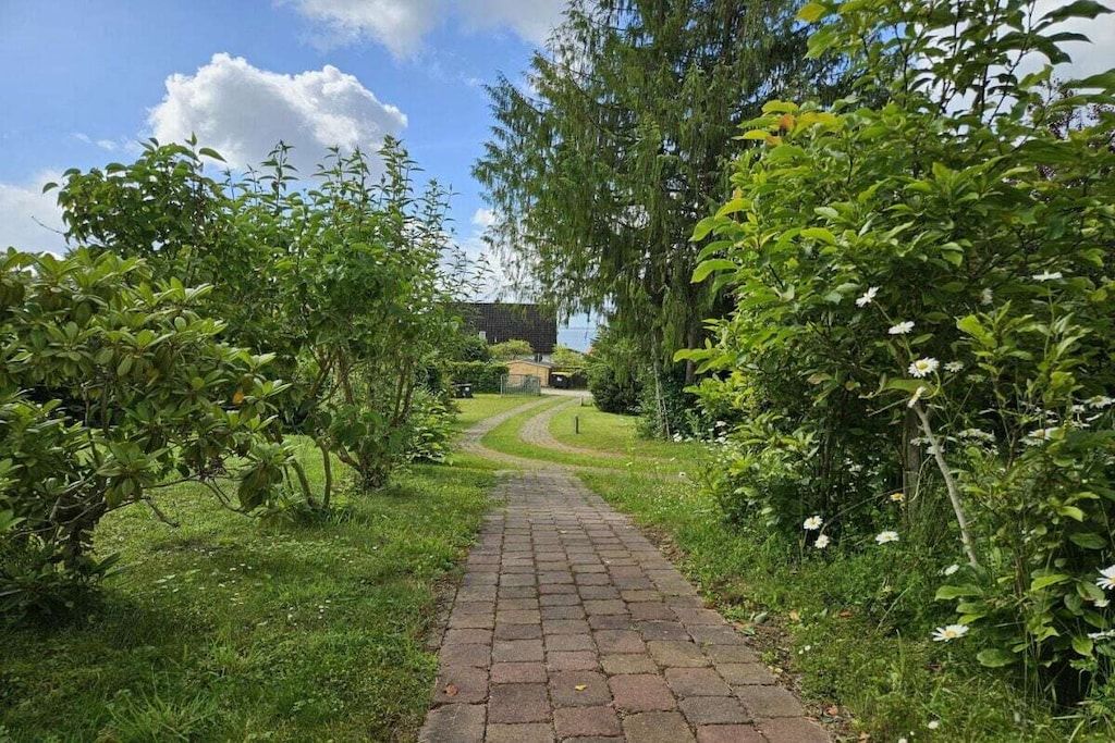 A paved pathway leading through a garden with dense foliage on both sides.