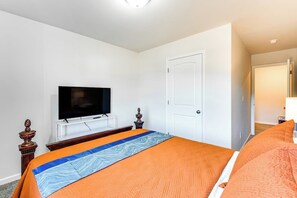 A hotel room with a bed, a television, a door, and a wardrobe.