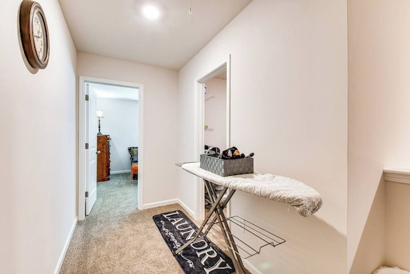 A laundry area with an ironing board, a basket, and a rug with 'laundry' written on it.