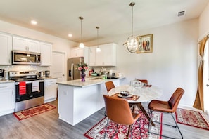 A modern kitchen with white cabinetry, stainless steel appliances, and a central island with seating.
