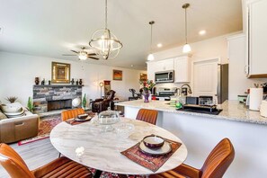 A modern kitchen with a central island, a dining area with a round table, and a fireplace.