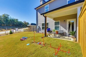 A residential property with a covered patio, a barbecue grill, and a lawn with a sprinkler system.