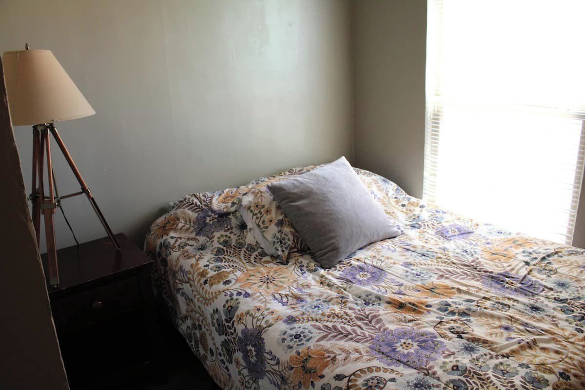 Une chambre à coucher avec un lit, une lampe et une fenêtre.