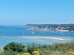 A coastal landscape with boats on the water, a sandy beach, and a forested hill in the background. - Cozy house between Trieux, GR34 & Bréhat (Lézardrieux)