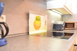 Una cocina moderna con placa de inducción integrada, cafetera y microondas.