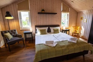 A room with a large bed, two bedside tables, a chair, and a lamp. - Holiday home with 2 bedrooms (Neustadt\/Holstein - OT Pelzerhaken)