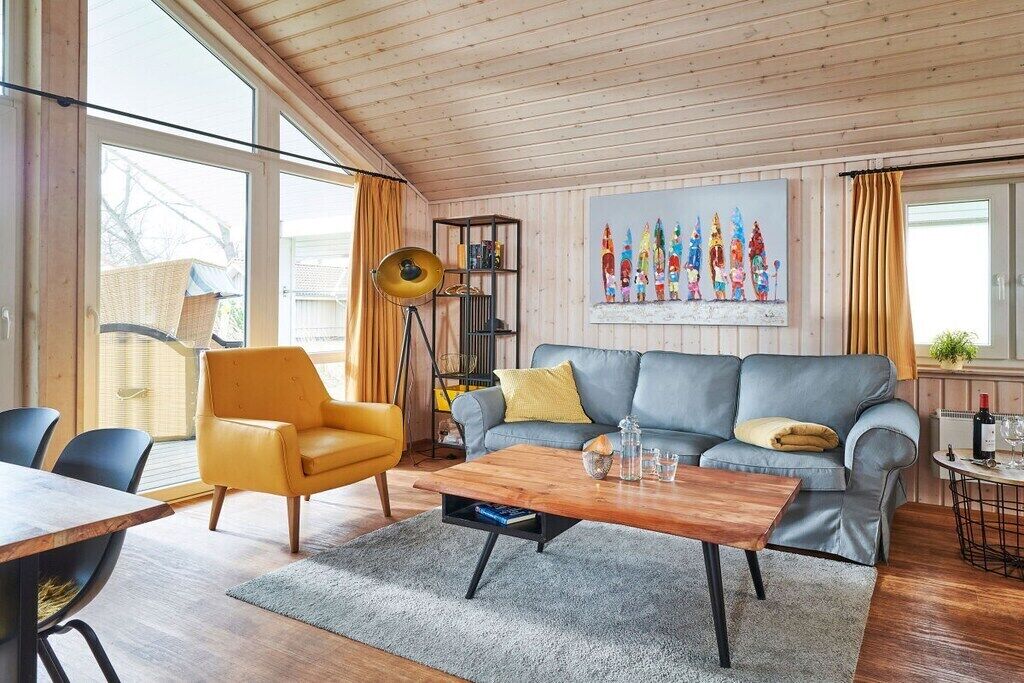 Ett modernt vardagsrum med en soffa, fåtölj, soffbord och en bokhylla.