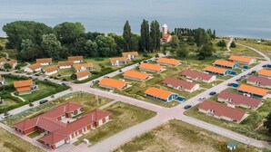 An aerial view of a coastal residential area with multiple houses, roads, and a lighthouse. - Holiday home with 2 bedrooms (Neustadt\/Holstein - OT Pelzerhaken)