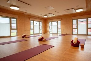 A spacious room with large windows, wooden flooring, and yoga mats arranged for practice. - Holiday home with 2 bedrooms (Neustadt\/Holstein - OT Pelzerhaken)