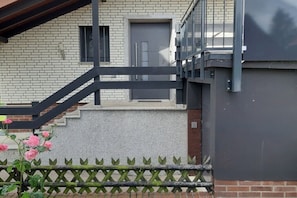 A building with a brick facade, a grey door, and a black metal staircase leading to a landing. - Holiday apartment with 2 bedrooms (Rinteln)