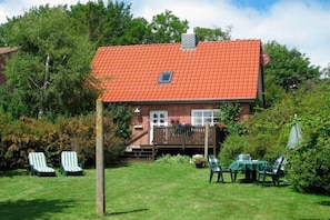 Ein Haus mit rotem Ziegeldach, einer Holzterrasse und einem Garten mit Gartenmöbeln.