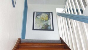 A wooden staircase with a white railing and a framed painting of a flower on the wall. - Holiday home in Fehmarn with swimming pool (Fehmarn)