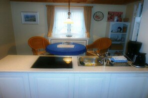 A small kitchen with a sink, a stove, and a dining area with two chairs. - Old Beach Warden's Office No. 1 (List)