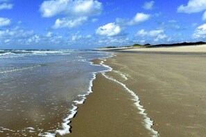 A beach with a wide sandy shore and gentle waves. - Old Beach Warden's Office No. 1 (List)