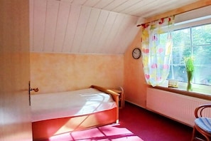 A small, single-bed room with a window, a chair, and a radiator. - Holiday apartment with 2 bedrooms (Ochtersum)