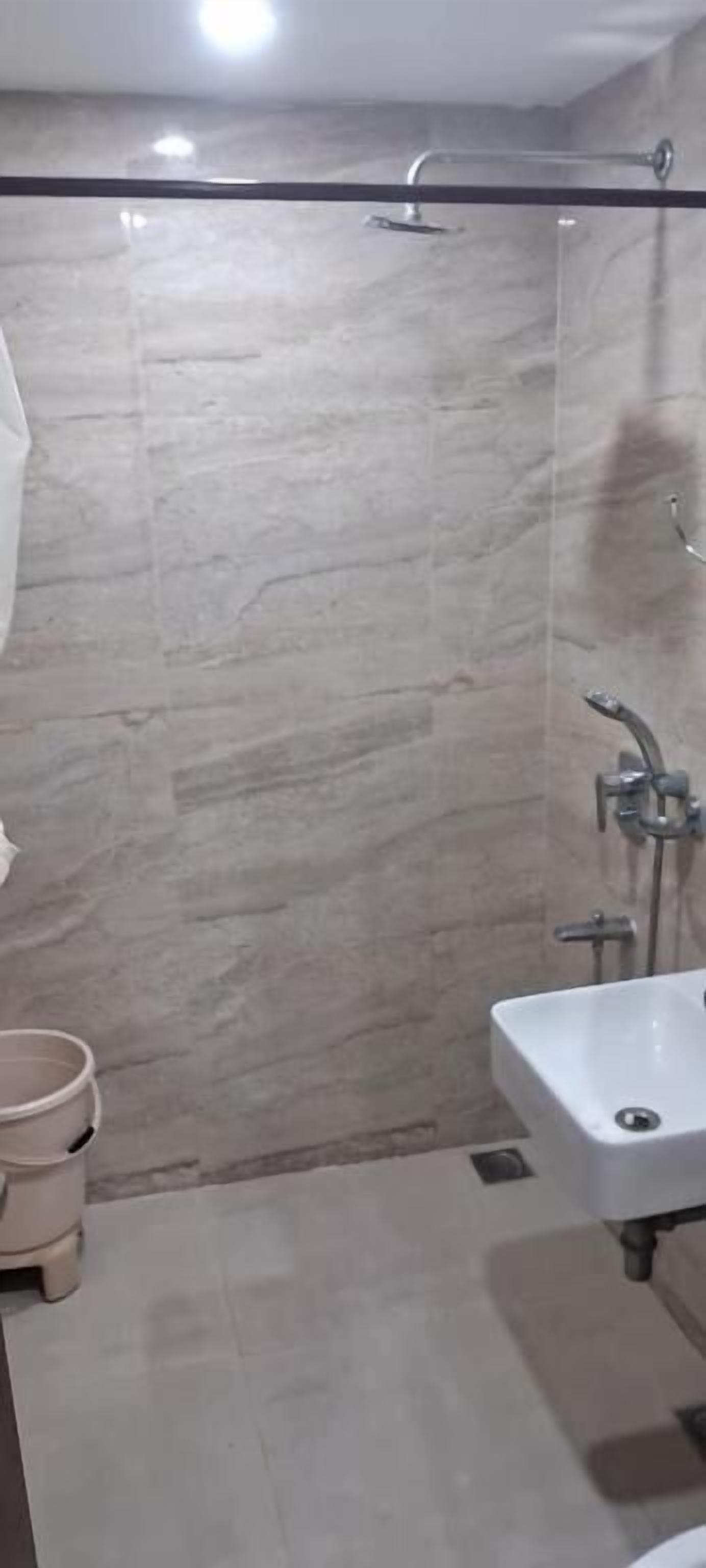Ein Badezimmer mit Duschkabine aus Glas, Waschbecken und Toilette.
