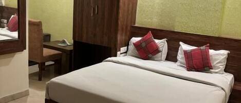 A bedroom with a large bed, a wardrobe, a ceiling fan, and an air conditioning unit.